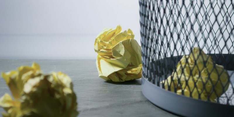 focus photo of yellow paper near trash can